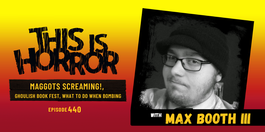 Max Booth looks at the camera as part of the podcast cover image for episode 440 of This Is Horror Podcast. Max wears glasses and a hat. The photo is shot in black and white and Max has a knowing smirk that complements his personality.
